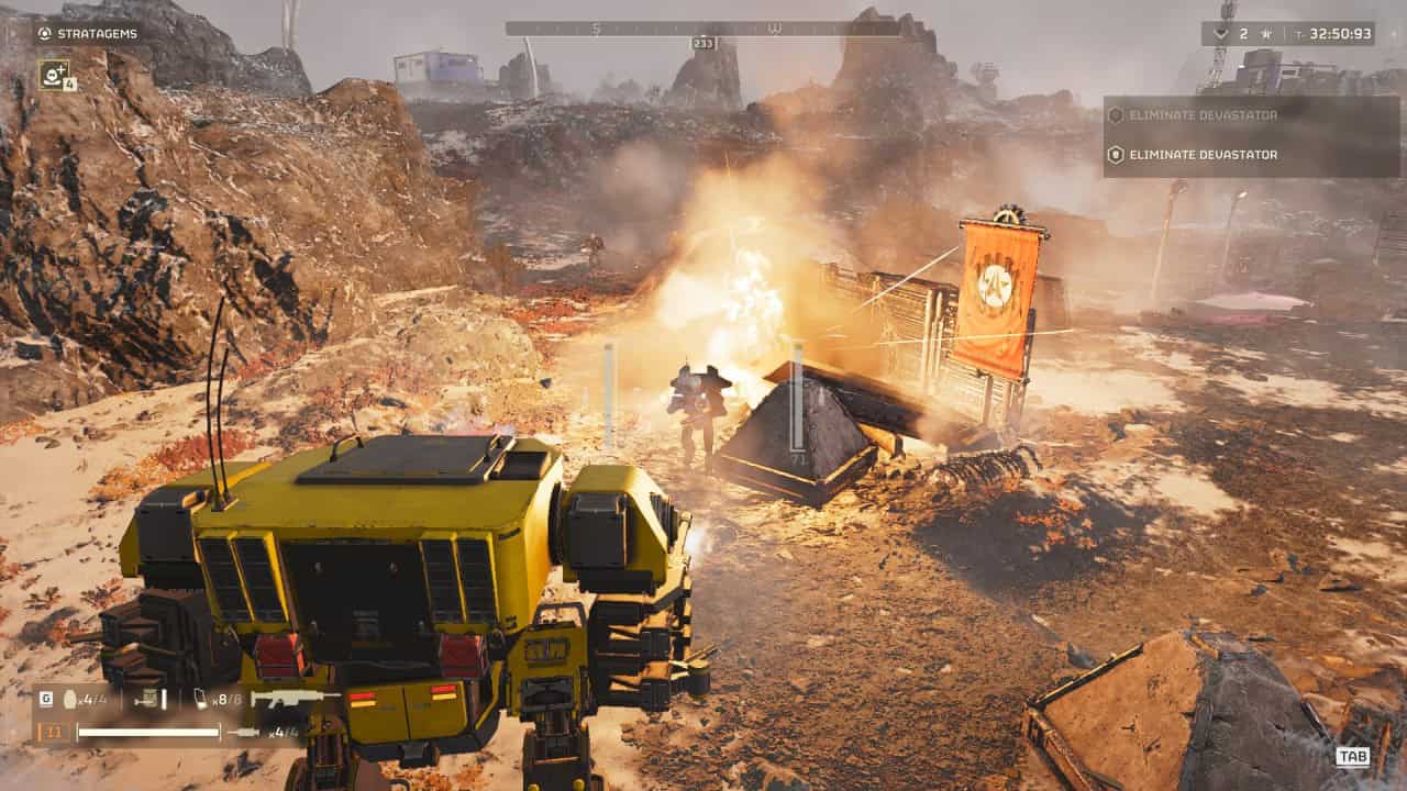 Two robots stand in a rugged, desert-like setting. One faces a blazing fire near a tent with a flag, while the other observes. The screen displays mission objectives: "Eliminate Dreadnator." This scene appears straight out of Helldivers 2.