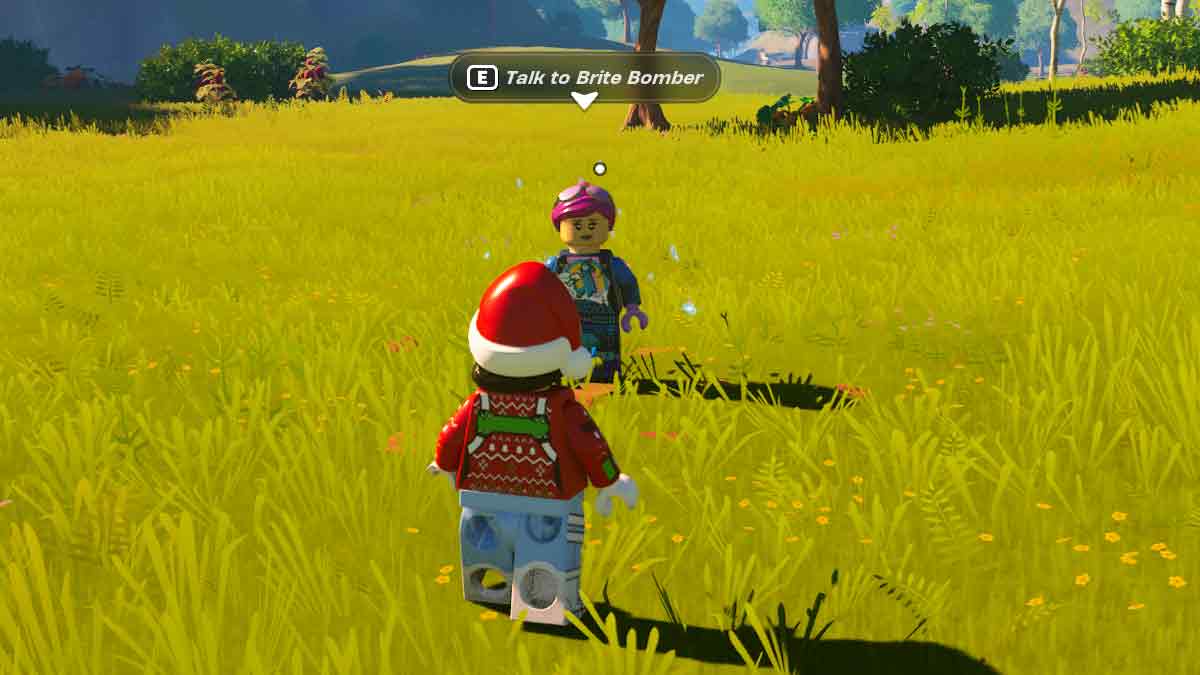 Un personnage LEGO en tenue de Père Noël s'approche d'un autre personnage LEGO nommé Brite Bomber dans un champ herbeux, à ce qui ressemble à un niveau Fortnite, avec une invite à appuyer sur « E » pour parler.