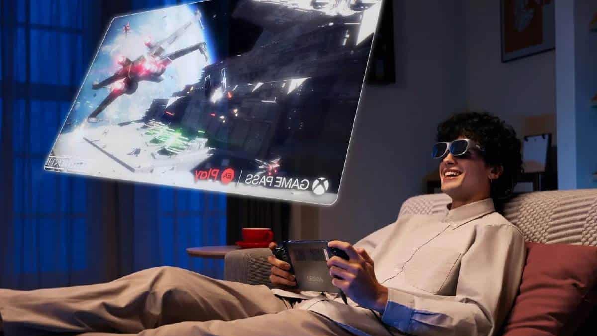 A man is playing a video game on a Lenovo Legion Go in front of a projection screen.