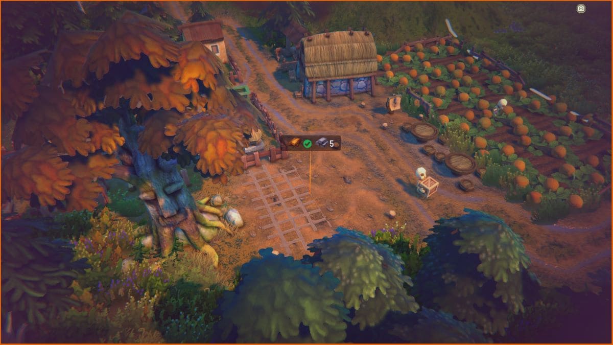 Fabledom review: top-down view of a village featuring a tree, a thatched barn, a vegetable garden, and various plants and structures along a winding dirt path.
